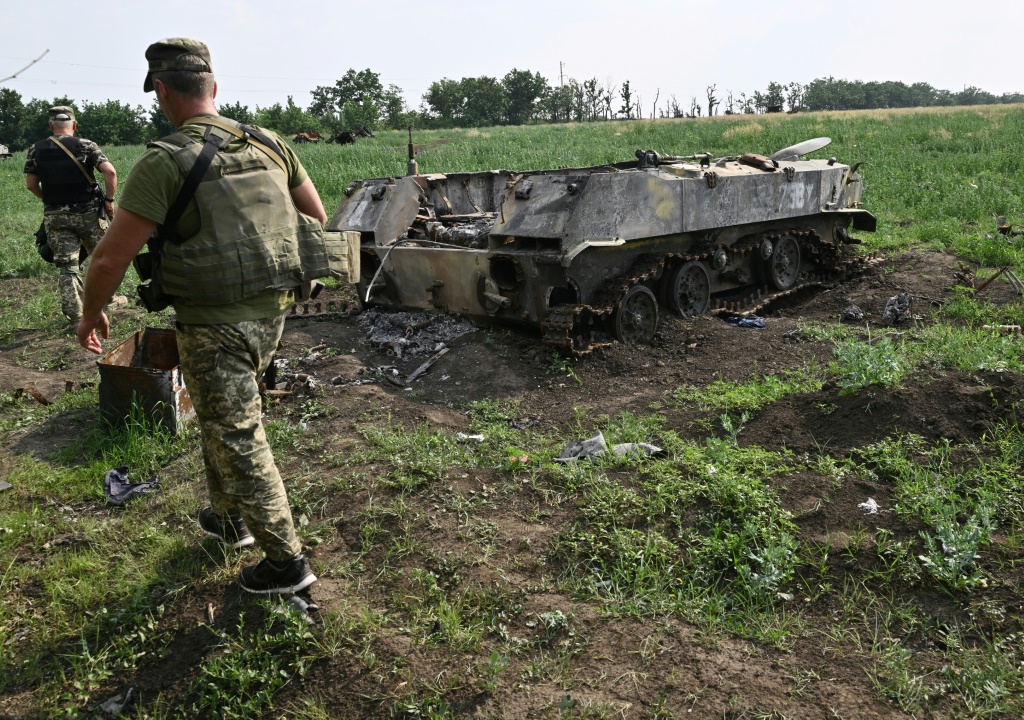 جندي أوكراني قرب دبابة روسية مدمرة في حقل إلى جنوب مدينة ميكولاييف في 12 حزيران/يونيو 2022 (ا ف ب)