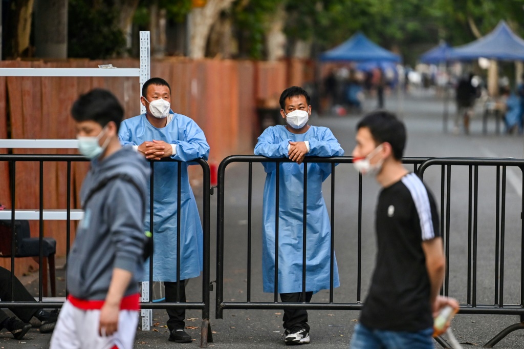 عاملان يراقبان عند مدخل حي سكني مغلق لاحتواء كوفيد-19 في شنغهاي في 16 حزيران/يونيو 2022 (ا ف ب)