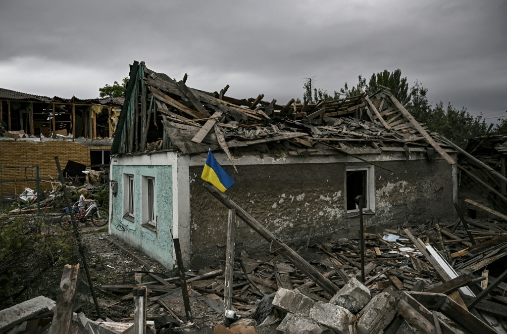 علم اوكراني أمام منزل مدمّر بضربة في دوبروبيليا في منطقة دونباس في شرق اوكرانيا في 15 حزيران/يونيو 2022 (ا ف ب)