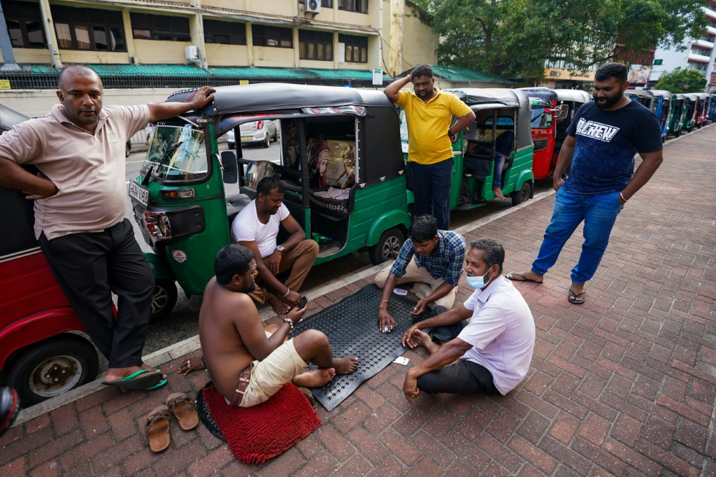 صورة مؤرخة في 18 حزيران/يونيو 2022 لمواطنين سريلانكيين يلعبون بالورق خلال انتظارهم في الدور لتعبئة وقود في كولومبو(ا ف ب)