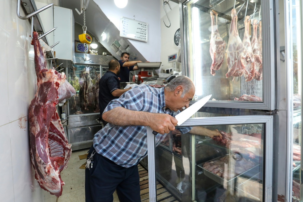 جزار في طهران يقطع اللحم في متجره في 15 حزيران/يونيو 2022 (ا ف ب)