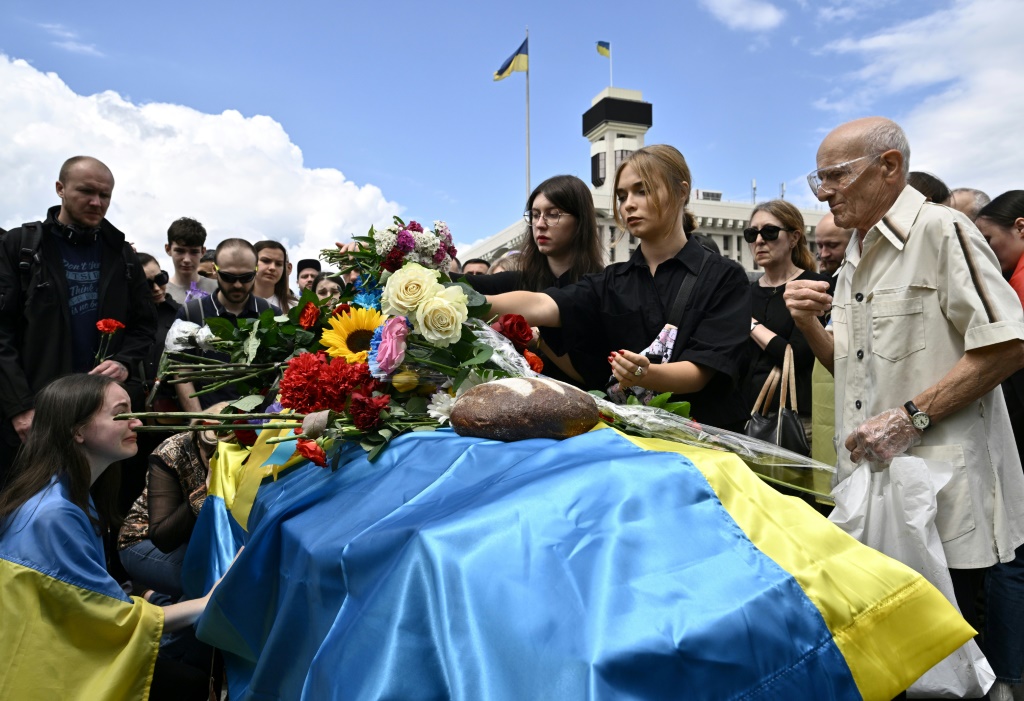 مجموعة أشخاص يقفون قرب نعش الجندي الأوكراني المقتول رومان راتوشني في كييف في 18 حزيران/يونيو 2022 (ا ف ب)