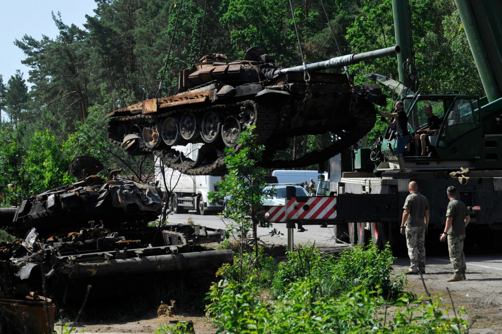   جنود أوكرانيون يتفقدون دبابة روسية مدمّرة في بلدة دميتريفكا في منطقة كييف في 20 حزيران/يونيو 2022 (ا ف ب)