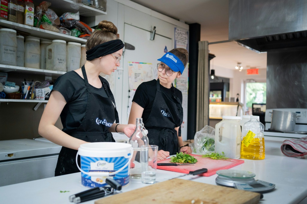 صوفيا روز آدامز (يمين) وشقيقتها أورلان تعملان في مقهى "لي غورماند" الواقع في منطقة مونتريال الكندية في 12 حزيران/يوليو 2022 (ا ف ب)