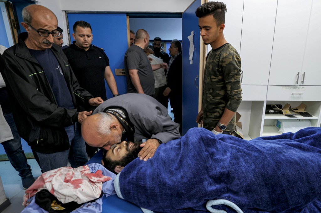 والد القتيل الفلسطيني علي حرب (27 عاماً) يقبّل جثمان ولده في مستشفى في سلفيت في الضفة الغربية المحتلة في حزيران/يونيو 2022 (ا ف ب).