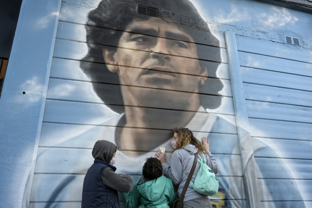  عشاق النجم الارجنتيني الراحل دييغو أرماندو مارادونا أمام لوحة جدارية له في بوينس أيرس في 22 حزيران/يونيو 2021 (اف ب).