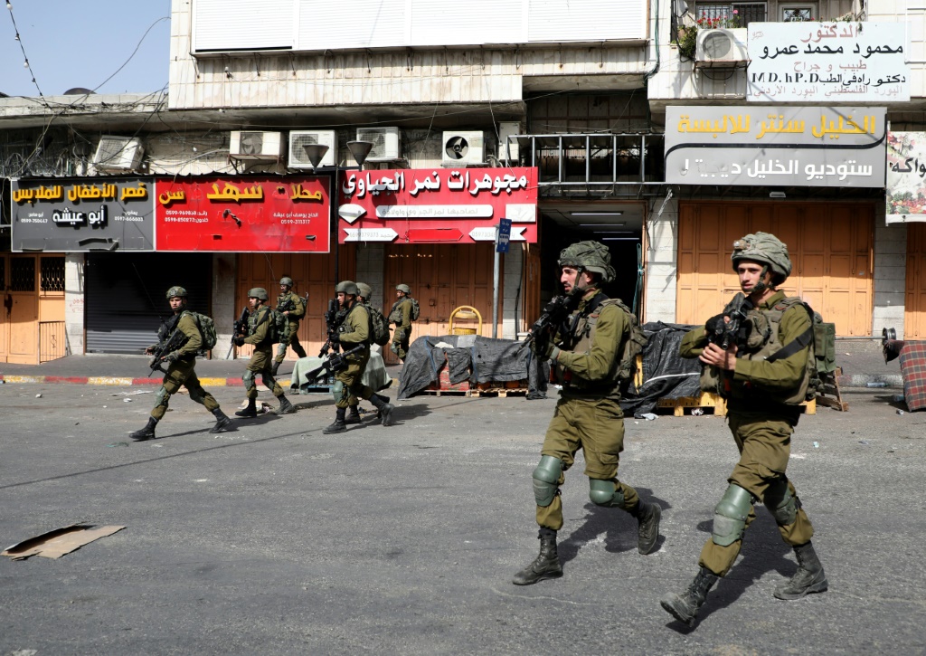    جنود إسرائيليون يمشون خلال مواجهات مع متظاهرين فلسطينيين في مدينة الخليل في الضفة الغربية المحتلة في 29 أيار/مايو 2022 ضد مسيرة الأعلام الإسرائيلية في القدس الشرقية المحتلة (ا ف ب)