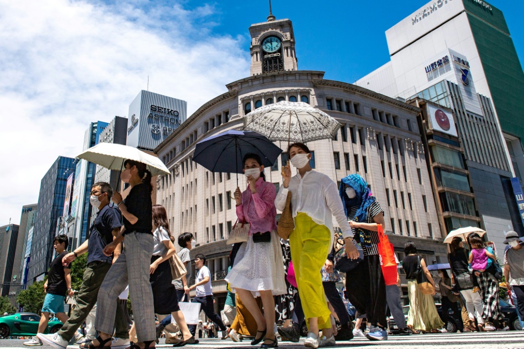  مارة في حي غينزا في طوكيو يستعينون بمظلات بسبب درجات الحرارة المرتفعة في 26 حزيران/يونيو 2022 (ا ف ب)