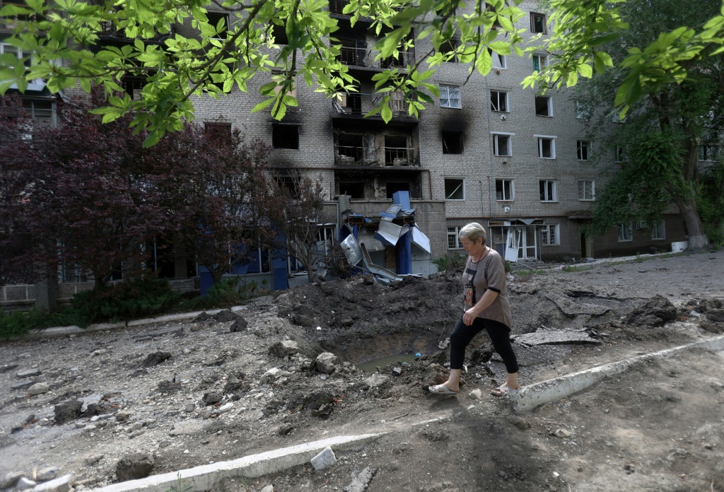 امرأة تمر أمام مبنى تعرض للقصف في سيفيرسك في منطقة دونيتسك في 23 حزيران/يونيو 2022 (ا ف ب)