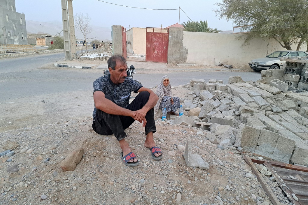 زوجان يجلسان تحت الأنقاض بعد الزلازل التي ضربت قرية ساية خوش في محافظة هرمزكان جنوب إيران (ا ف ب)