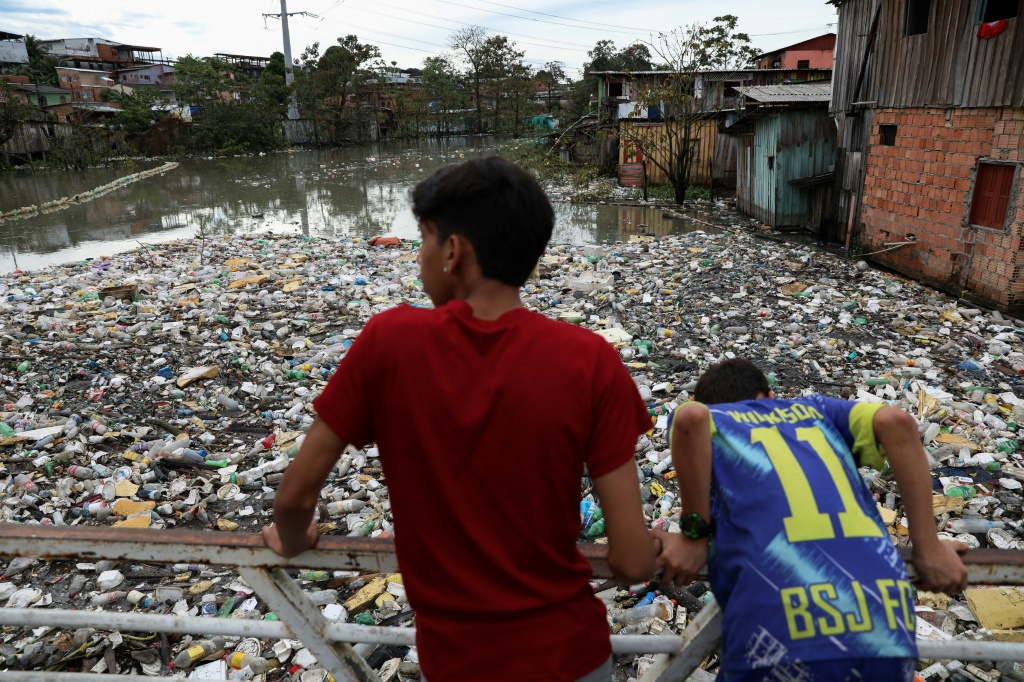 سكان ماناوس، أكبر مدينة في البرازيل في غابات الأمازون المطيرة، ينظرون إلى نهر من القمامة - وهو أمر شائع في المدينة - في 5 يونيو 2022 (ا ف ب).