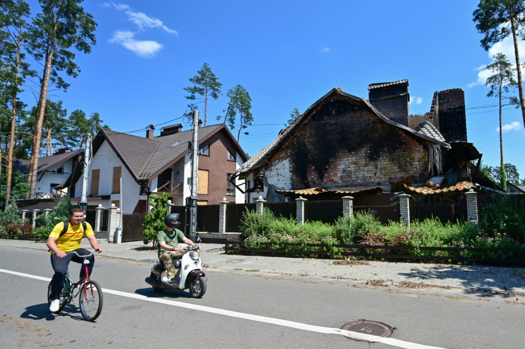 لقطة لأشخاص يمرون من أمام منزل تدمّر جراء المعارك في إربين مطلع نيسان/أبريل بتاريخ 1 تموز/يوليو 2022 (أ ف ب)