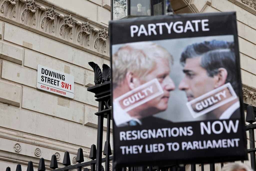 لافتة تطالب باستقالة رئيس الوزراء بوريس جونسون (يسار) ووزير المالية ريشي سوناك وتتّهمهما بالكذب على البرلمان (ا ف ب)