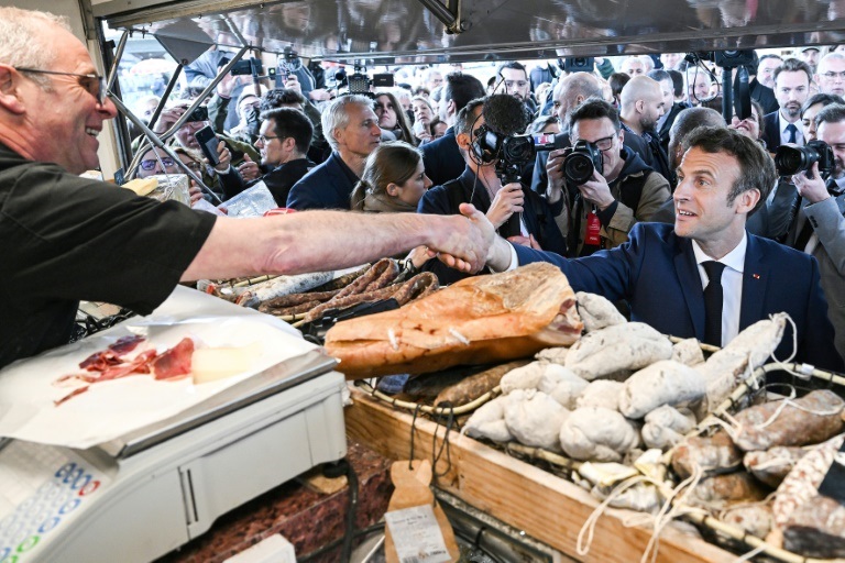 الرئيس الفرنسي إيمانويل ماكرون يصافح بائع لحوم مقددة في سوق شعبية في باربازان ديبا جنوب فرنسا في 29 نيسان/ابريل 2022 (ا ف ب)