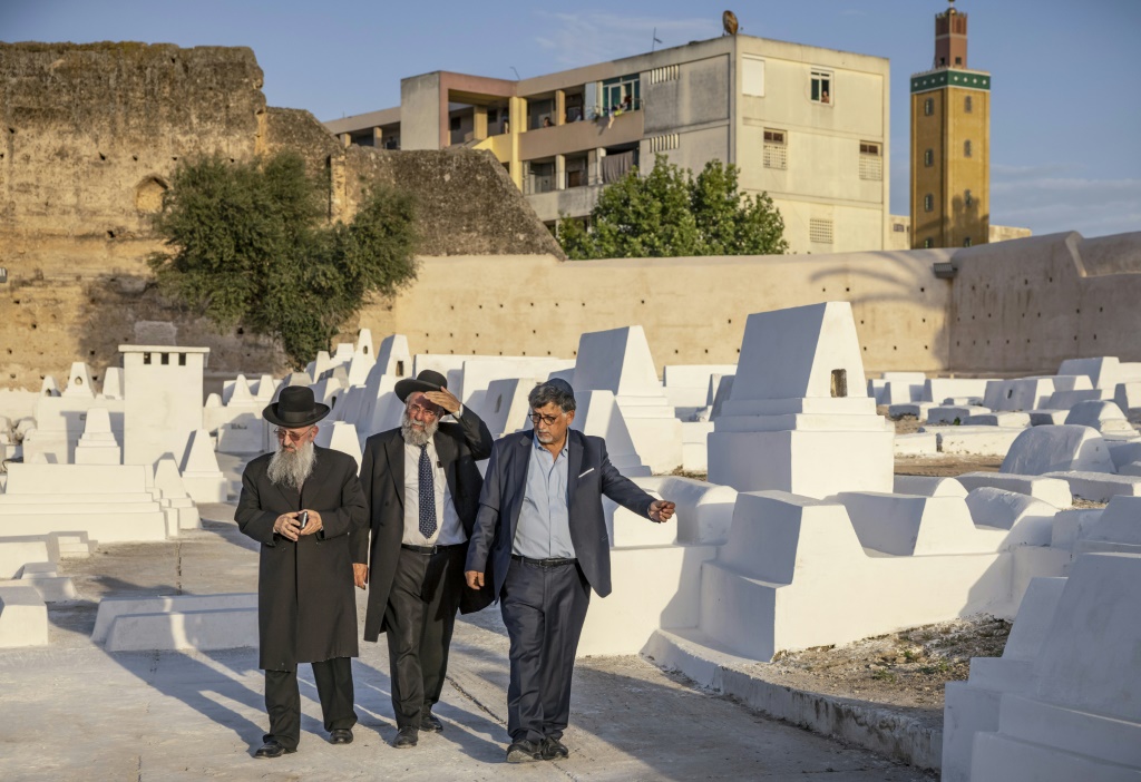 أفراد من الجالية اليهودية يمرون بمقابر في مقبرة يهودية في مدينة مكناس شمال المغرب في 18 مايو 2022 (أ ف ب)