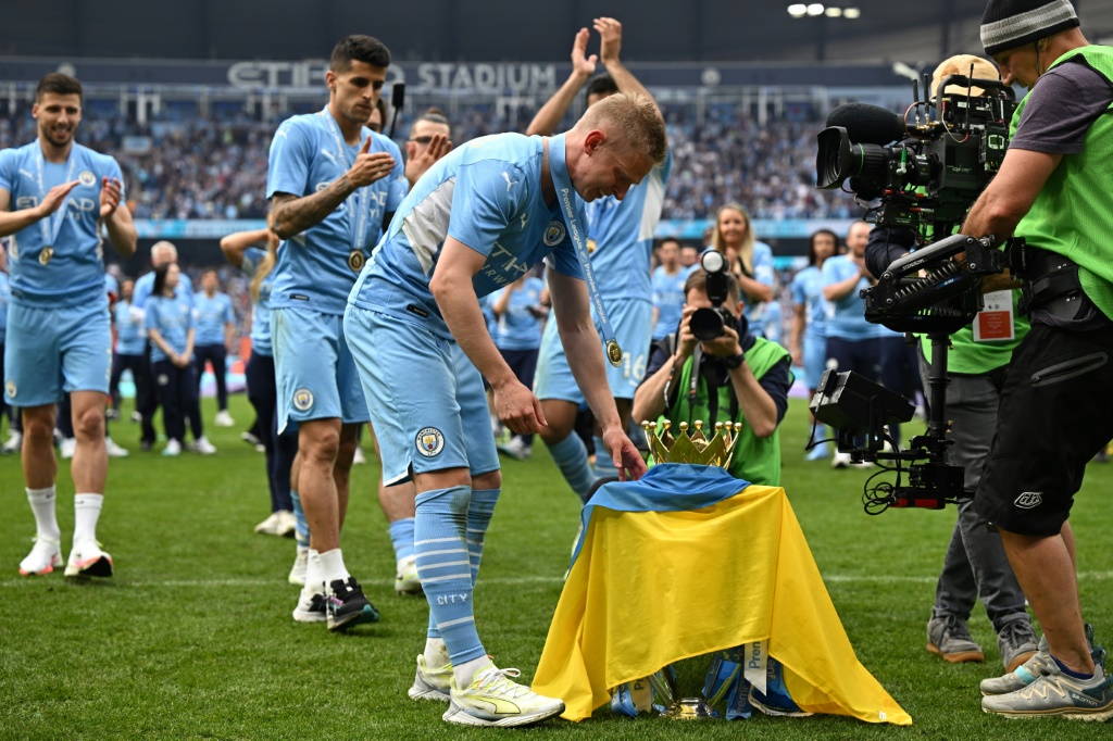 المدافع الاوكراني اولكسندر زينتشينكو يلف كأس الدوري الانكليزي لكرة القدم بعلم بلاده. مانشستر في 22 ايار/مايو 2022 (ا ف ب)