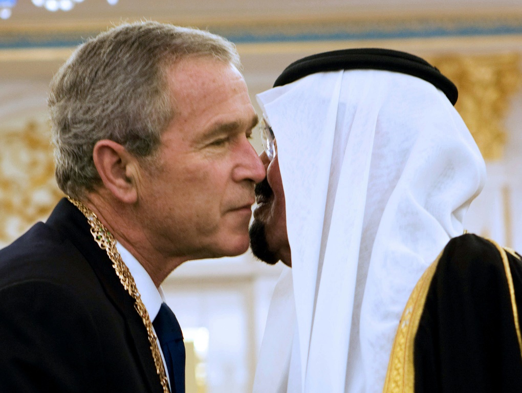 الملك السعودي عبد الله بن عبد العزيز آل سعود (إلى اليمين) يحتضن الرئيس الأمريكي جورج دبليو بوش على الخد عند وصوله في زيارة إلى المملكة الغنية بالنفط في مايو 2008 (أ ف ب)