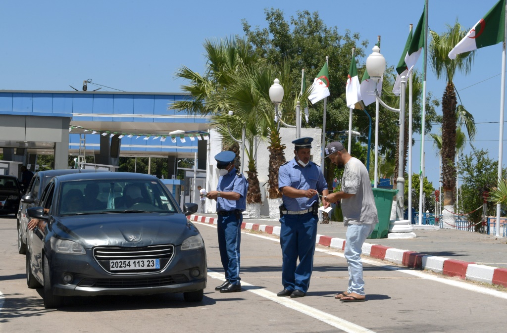 عناصر امن تونسيون يدققون في اوراق سائق عند معبر طبرقة مع الجزائر بعد اعادة فتح الحدود البرية في 15 تموز/يوليو 2022 (أ ف ب)
