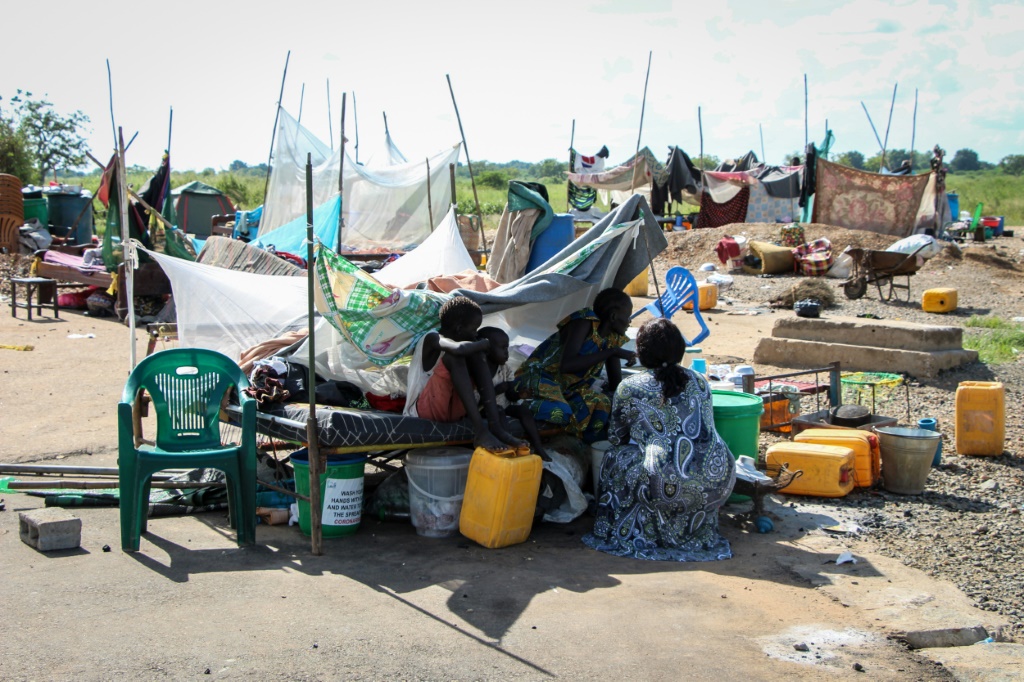 نازحون جالسون قرب أغراضهم على طريق بعد إجلائهم بسبب فيضانات في جوبا في جنوب السودان في 28 أيلول/سبتمبر 2021 (ا ف ب)