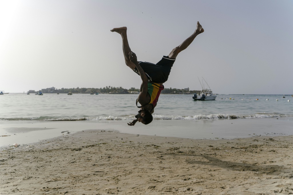 ماليك العضو في فرقة "سينسيرك" للسيرك البالغ 30 عاما يتدرب على تأدية حركات بهلوانية على شاطئ نغو في العاصمة السنغالية داكار في 10 أيار/مايو 2022 (ا ف ب)