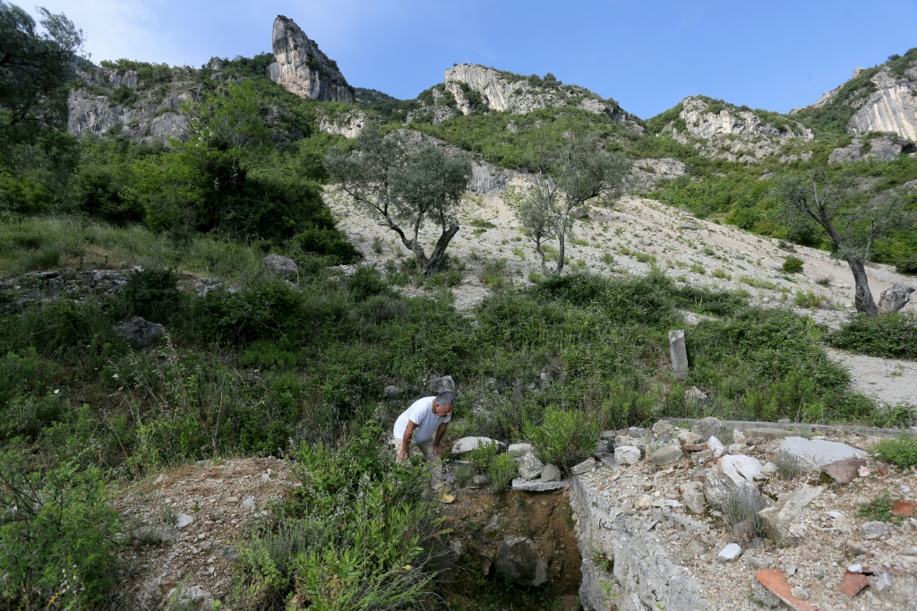 صورة مؤرخة في 13 حزيران/يونيو 2022 لعالم الآثار اسكندر موتساي يتفقد الحفر التي خلفها لصوص لدى نهبهم كنيسة مريم العذراء في كورشه الألبانية (ا ف ب)