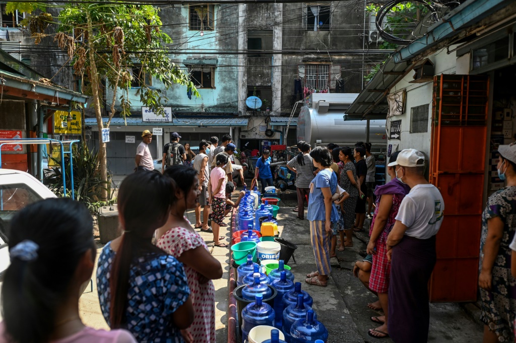 بورميون ينتظرون في رانغون لملء أوعيتهم بالماء بعد تعطل الإمدادات بسبب انقطاع التيار الكهربائي في المدينة في 14 آذار/مارس 2022 (ا ف ب)