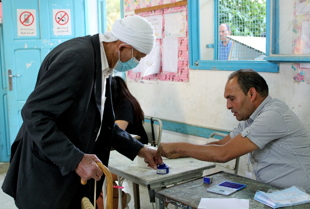 مسؤول في مركز اقتراع تونسي في القصرين يساعد مسنًا خلال استفتاء على مشروع دستور طرحه رئيس البلاد، في 25 تموز/يوليو 2022 (أ ف ب)