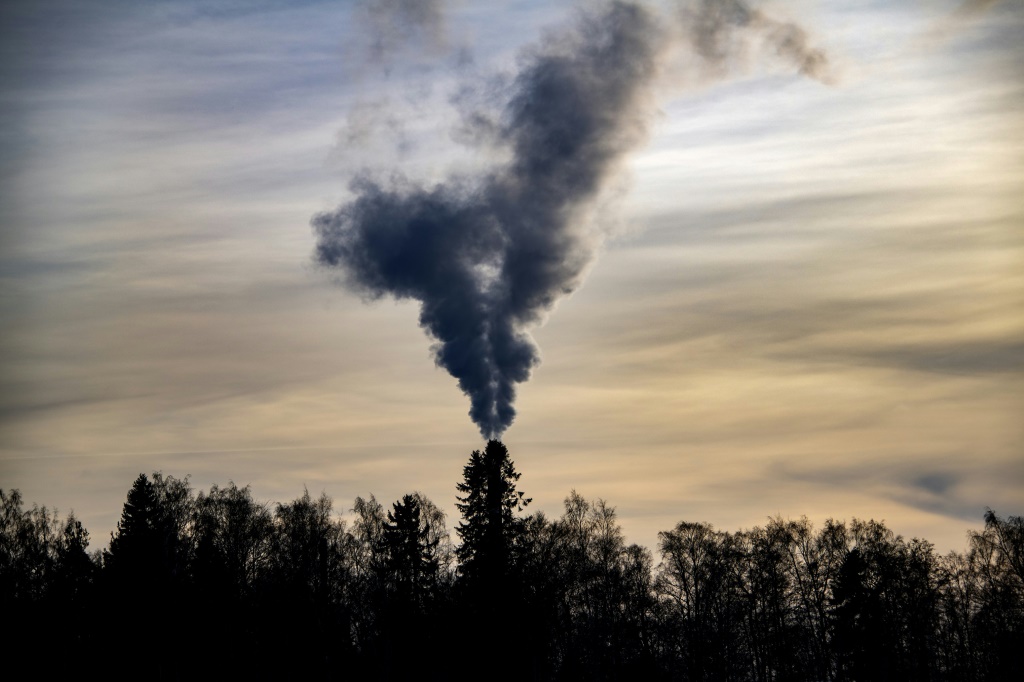   دخان يتصاعد فوق الأشجار من مدخنة مصنع في ساندوم (فنلندا) في 9 آذار/مارس 2022. (أ ف ب)