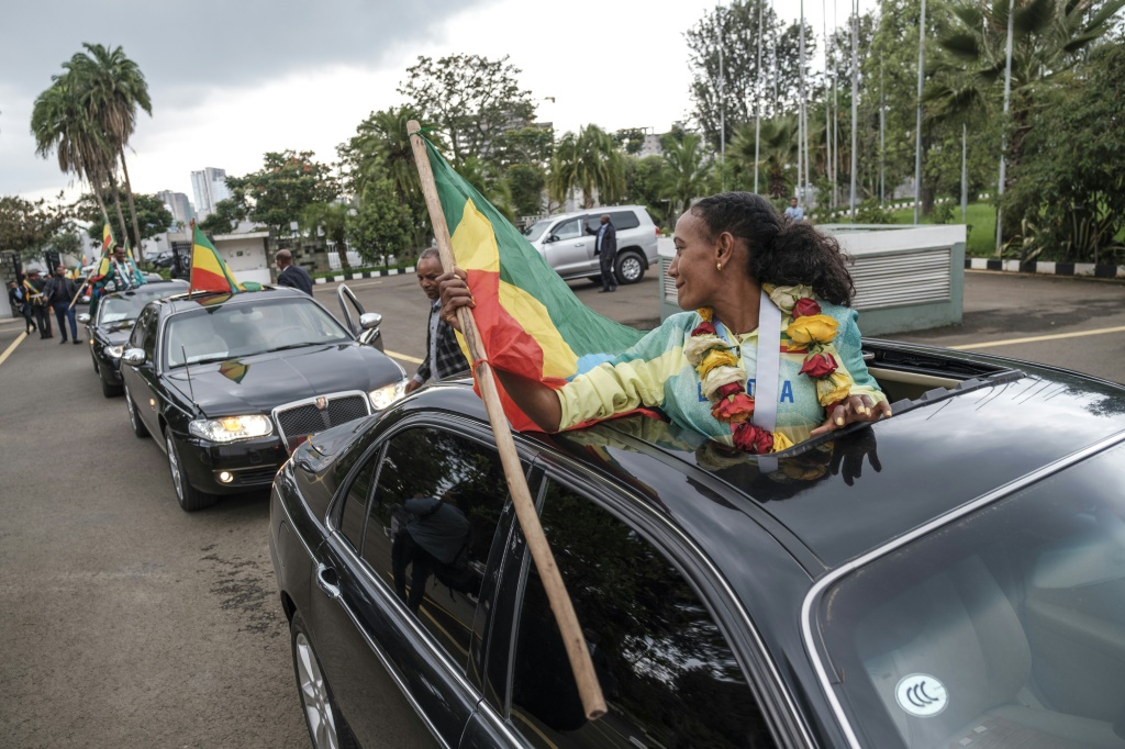 العداءة الإثيوبية غوتايتوم جبريسلاسي المتوجة بذهبية الماراثون تحمل علم بلادها داخل سيارة خلال حفل رسمي لتكريم العدائين المتوجين في بطولة العالم لألعاب القوى في مدينة يوجين الأميركية، في أديس أبابا في 28 تموز/يوليو 2022 (اف ب).