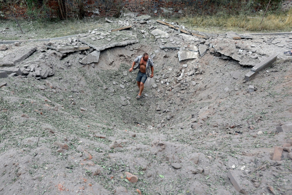    رجل يسير في حفرة عقب هجوم صاروخي على بلدة كوستيانتينيفكا (ا ف ب)