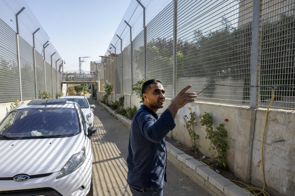 الفلسطيني سعدات غريب يشير إلى الممر المسيج الذي يضطر إلى سلوكه للخروج من منزله في الضفة الغربية المحتلة في 19 تموز/يوليو 2022 (أ ف ب)