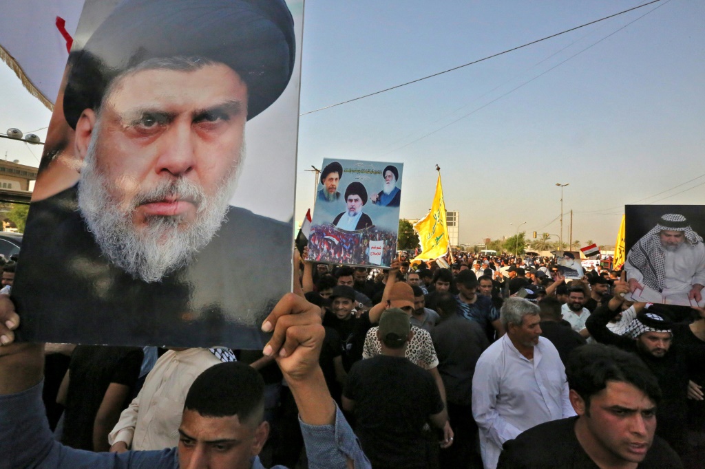 أنصار رجل الدين العراقي مقتدى الصدر يلوحون بملصقات له خلال تجمع حاشد في المنطقة الخضراء ببغداد يوم الاثنين (ا ف ب)