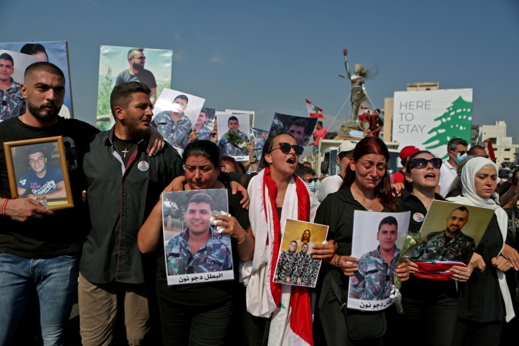    افراد من عائلات عناصر فوج الاطفاء، الذين قتلوا في انفجار مرفأ بيروت، يحملون صورهم في الرابع من آب/اغسطس 2021 في مسيرة احياء لذكرى مرور عام على الانفجار المروع. (أ ف ب)