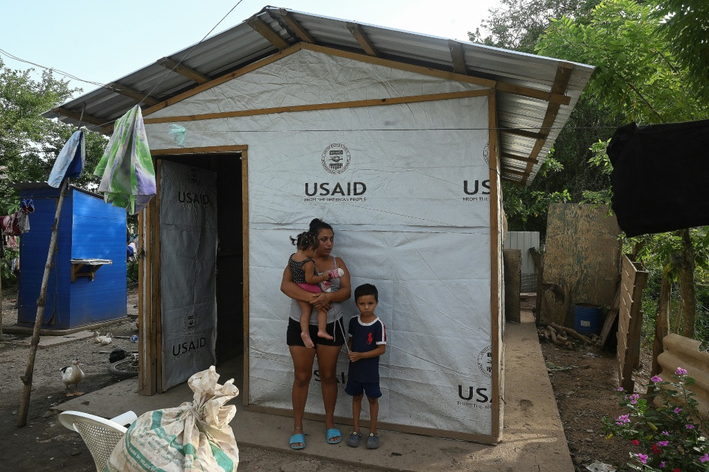  ساندرا راموس (22 عامًا) مع طفليْها خارج كوخ مؤقت بنته الوكالة الأميركية للتنمية الدولية على ضفاف نهر أولوا في غرب هندوراس في 15 تموز/يوليو 2022 (ا ف ب)