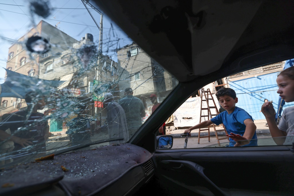 أطفال فلسطينيون ينظرون إلى سيارة دُمّرت خلال القتال بين الجهاد الإسلامي وإسرائيل في 8 آب/أغسطس 2022 في مخيم جباليا للاجئين شمال قطاع غزة (ا ف ب)   