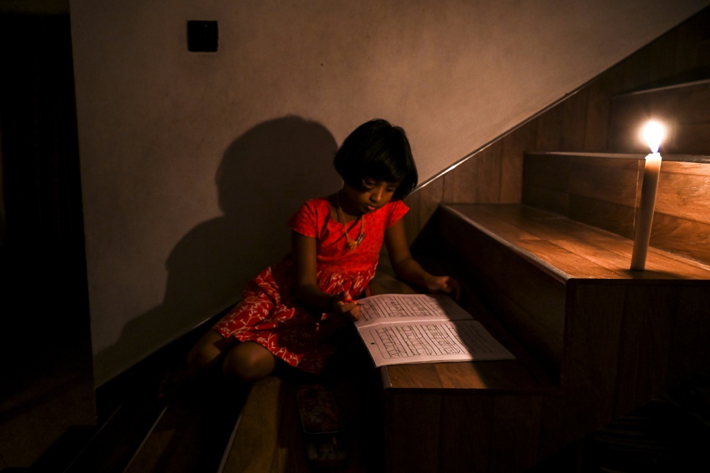 فتاة ترسم على ضوء الشمعة خلال انقطاع التيار الكهربائي في بياغاما إحدى ضواحي العاصمة السريلانكية كولومبو في 18 آب/أغسطس 2022 (ا ف ب)