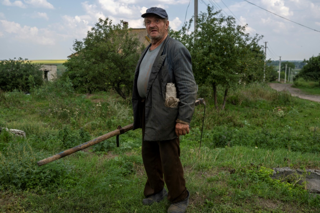 مزارع قرب قريتهغير البعيدة عن خط المواجهة في منطقة دونباس في أوكرانيا حيث يحاول مواصلة العمل رغم الخطر، في 11 آب/أغسطس 2022 (أ ف ب)