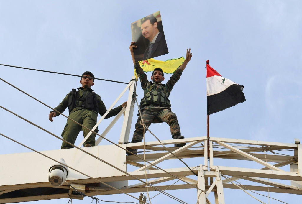 جندي سوري يرفع شارة النصر حاملا صورة للرئيس السوري بشار الأسد قرب مدينة كوباني في شمال سوريا في 19 تشرين الأول/أكتوبر 2019 (ا ف ب)