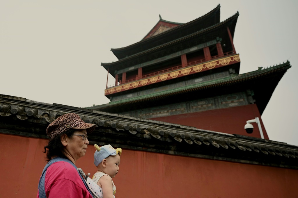 صورة مؤرخة في 27 تموز/يوليو 2022 لامرأة تحمل ابنها في بكين (ا ف ب)