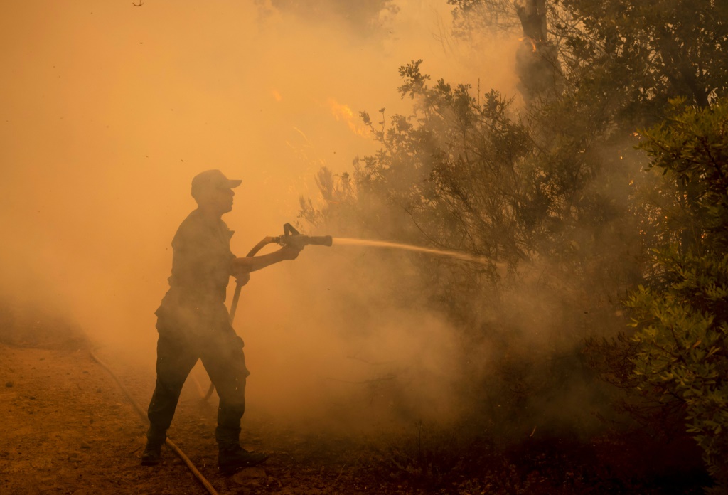 تكافح فرق الإطفاء للسيطرة على الحرائق بمساعدة طائرة عسكرية لمنع تمددها إلى المناطق السكنية (ا ف ب)