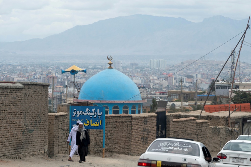 رجال أفغان يمشون قرب مسجد في 18 آب/أغسطس 2022 في ضواحي كابول (أ ف ب)