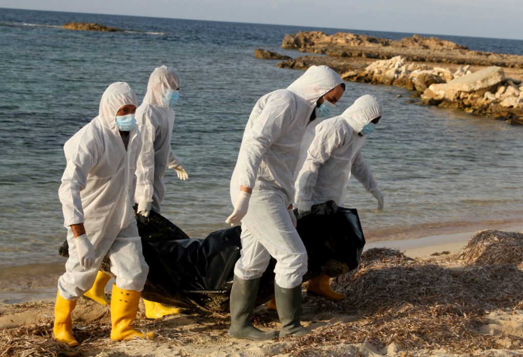عاملون صحيون ليبيون ينقلون جثث مهاجرين غرقوا أثناء محاولة عبورهم البحر المتوسط إلى أوروبا قبالة شواطئ مدينة صبراتة على مسافة 120 كيلومترا غرب طرابلس بتاريخ 25 تشرين الثاني/نوفمبر 2021 (أ ف ب)