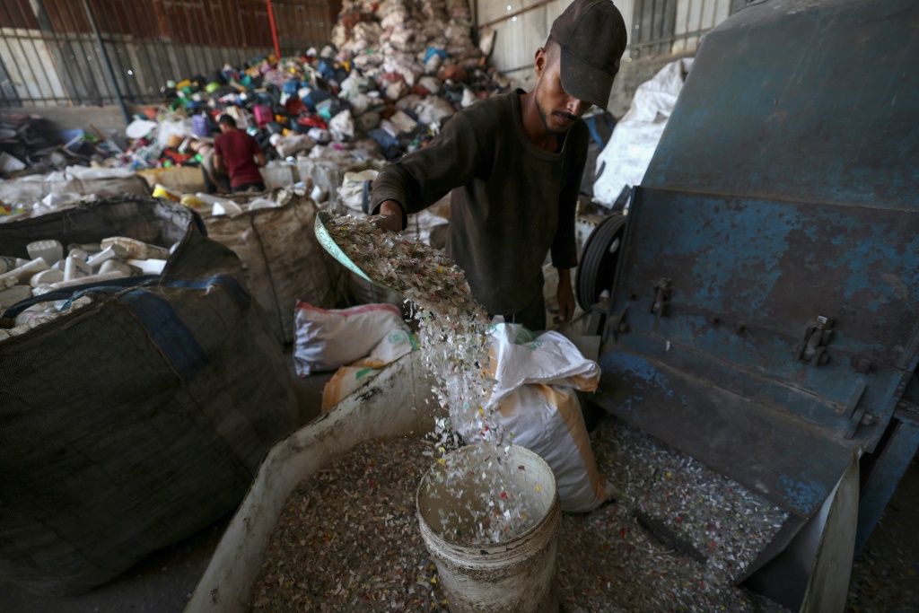 عامل فلسطيني يشعل النار في حوض يضم طنا من البلاستيك لإنتاج وقود في قطاع غزة في 23 آب/أغسطس 2022 (اف ب)