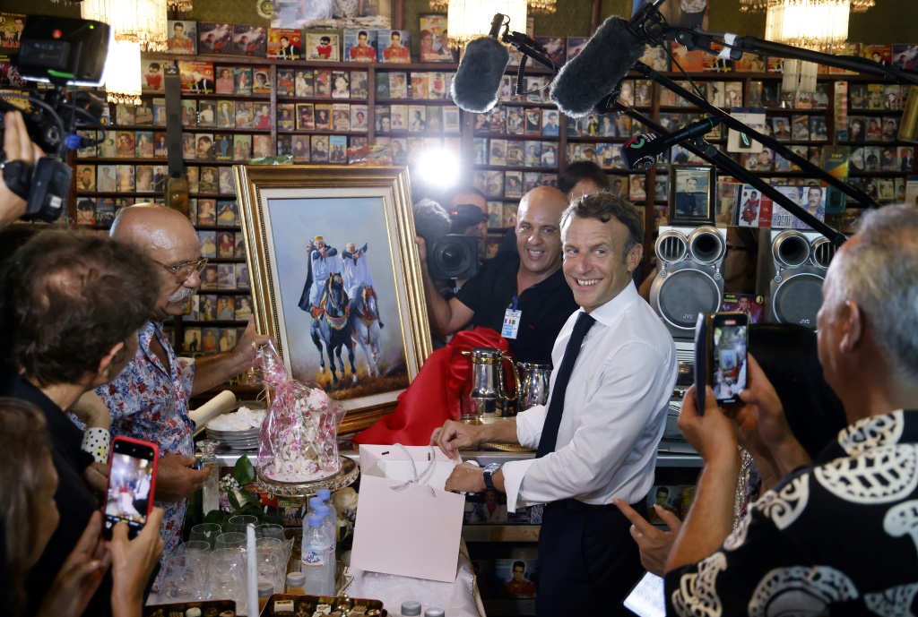 الرئيس الفرنسي إيمانويل ماكرون يتلقى هدية من بوعلام بن حوا صاحب إستديو "ديسكو مغرب" في وهران في 27 آب/أغسطس 2022 في اليوم الأخير من زيارة للجزائر (ا ف ب)