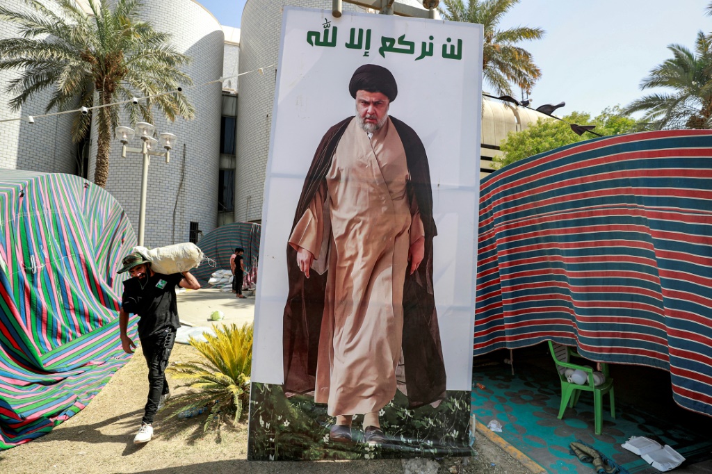 أحد أنصار الصدر يحمل أغراضا أثناء مغادرته المنطقة الخضراء في بغداد (ا ف ب)