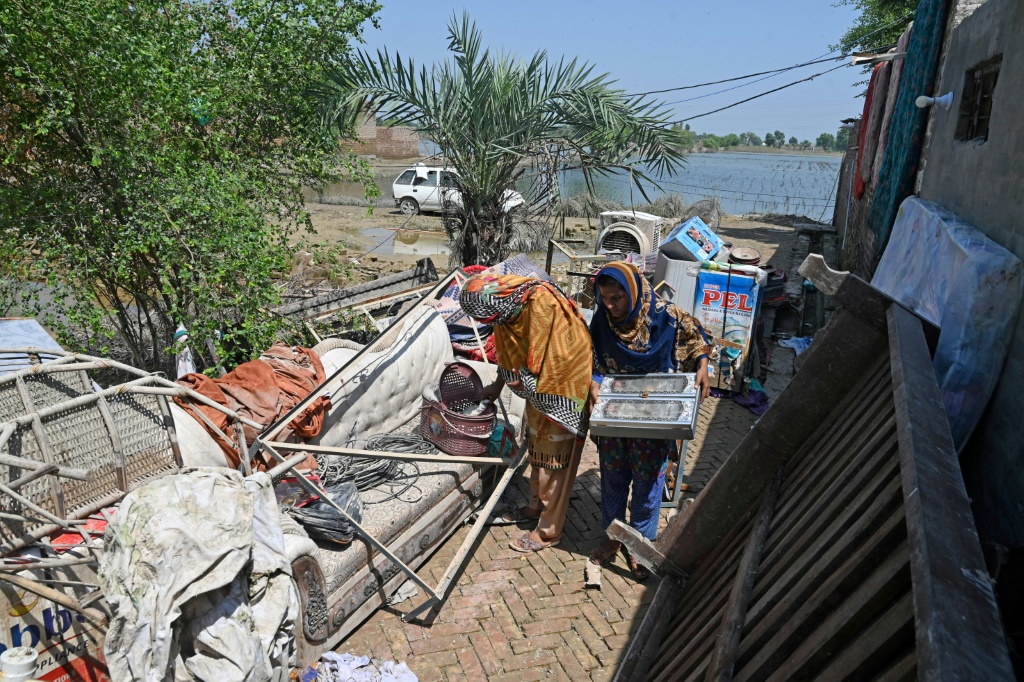 أفراد من عائلة حسين يحاولون إنقاذ ممتلكاتهم من منزلهم الذي دمرته الفيضانات في فازيلبور بإقليم البنجاب (ا ف ب)