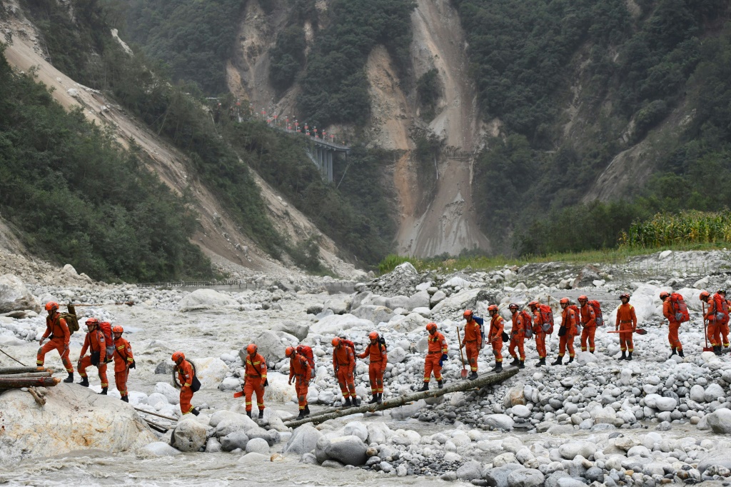 مسعفون يعبرون مجرى مياه للوصول إلى منطقة متضررة من الزلزال في مقاطعة سيتشوان في الصين في السادس من أيلول/سبتمبر 2022 (ا ف ب)