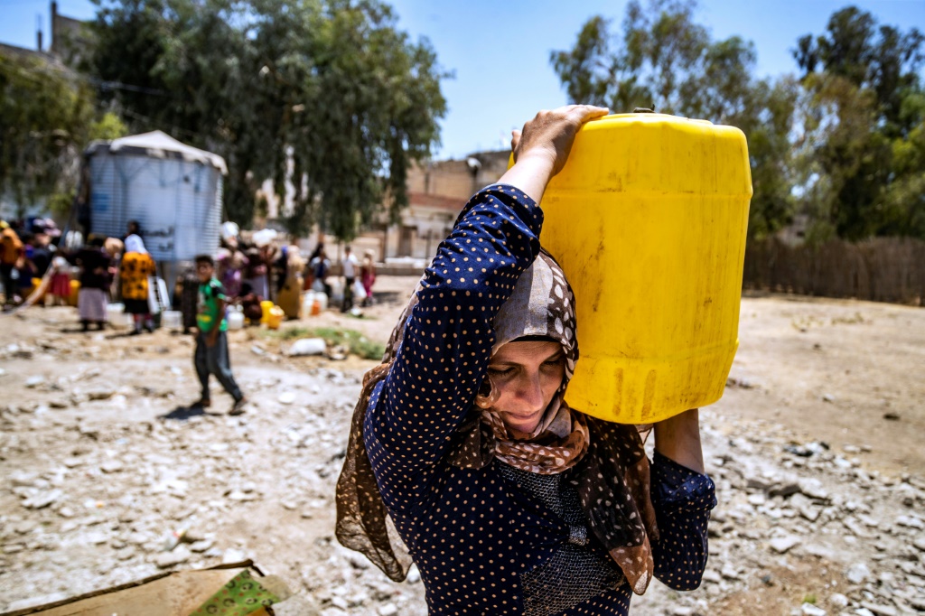 سيدة تحمل عبوة بلاستيكية مملوءة بالمياه في مدينة الحسكة في شمال شرق سوريا في 8 تموز/يوليو 2021 على خلفية أزمة مياه شهدتها المنطقة حينها (ا ف ب).