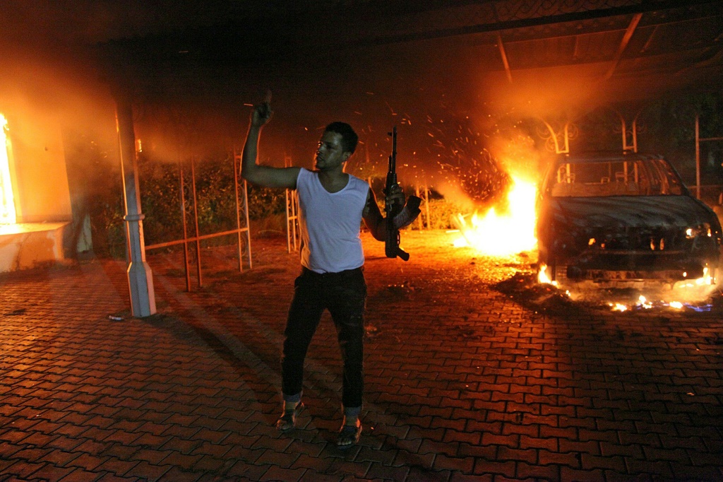 حرائق مشتعلة في مبان وسيارات ورجل مسلح في المجمع الدبلوماسي الأميركي في بنغازي بعد مهاجمته في 11 أيلول/سبتمبر 2022 (ا ف ب)
