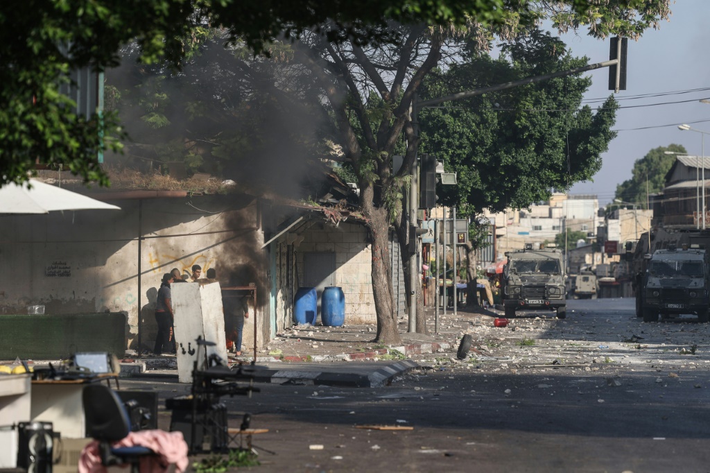 شبان فلسطينيون يختبئون وراء ساتر خلال مواجهات مع القوات الإسرائيلية خلال عملية للجيش الإسرائيلي في الضفة الغربية المحتلة في التاسع من آب/اغسطس 2022 (ا ف ب)